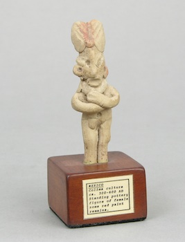 Appraisal: A Mexican Pottery Figurine on a Wood Stand An unglazed