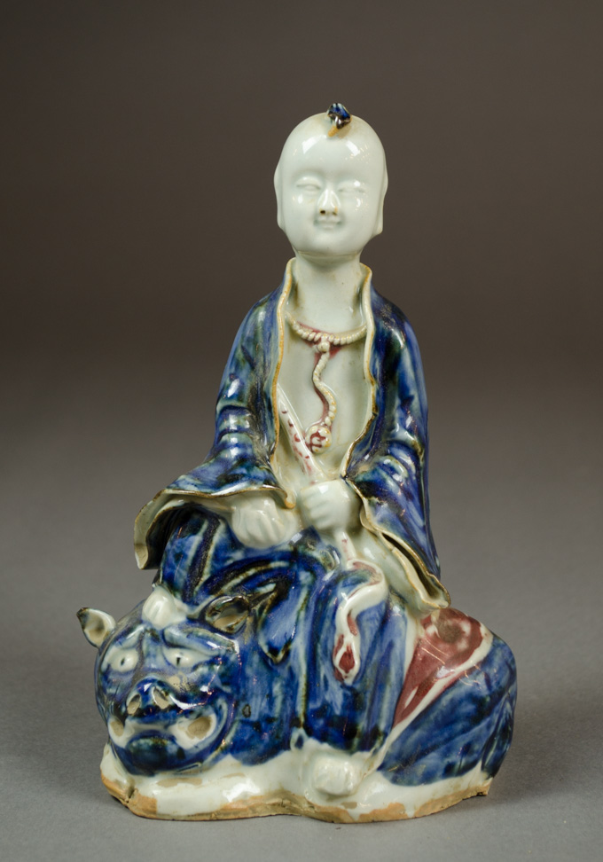 Appraisal: CHINESE PORCELAIN FIGURINE depicting a seated child holding a flute