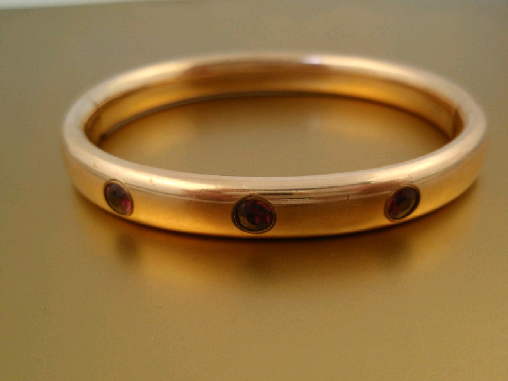 Appraisal: A yellow metal hinged bangle set with three purple stones