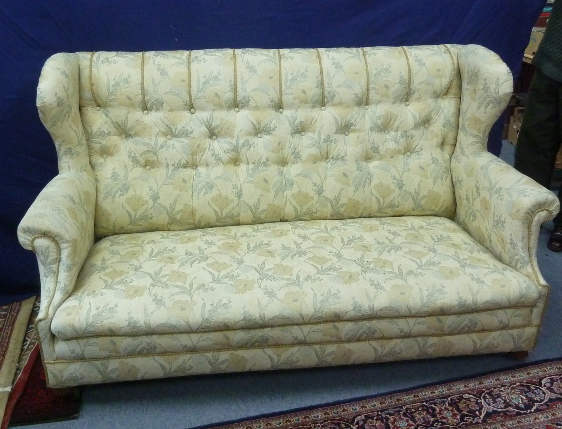 Appraisal: An upholstered wing-back settee with button-back scroll arms and on