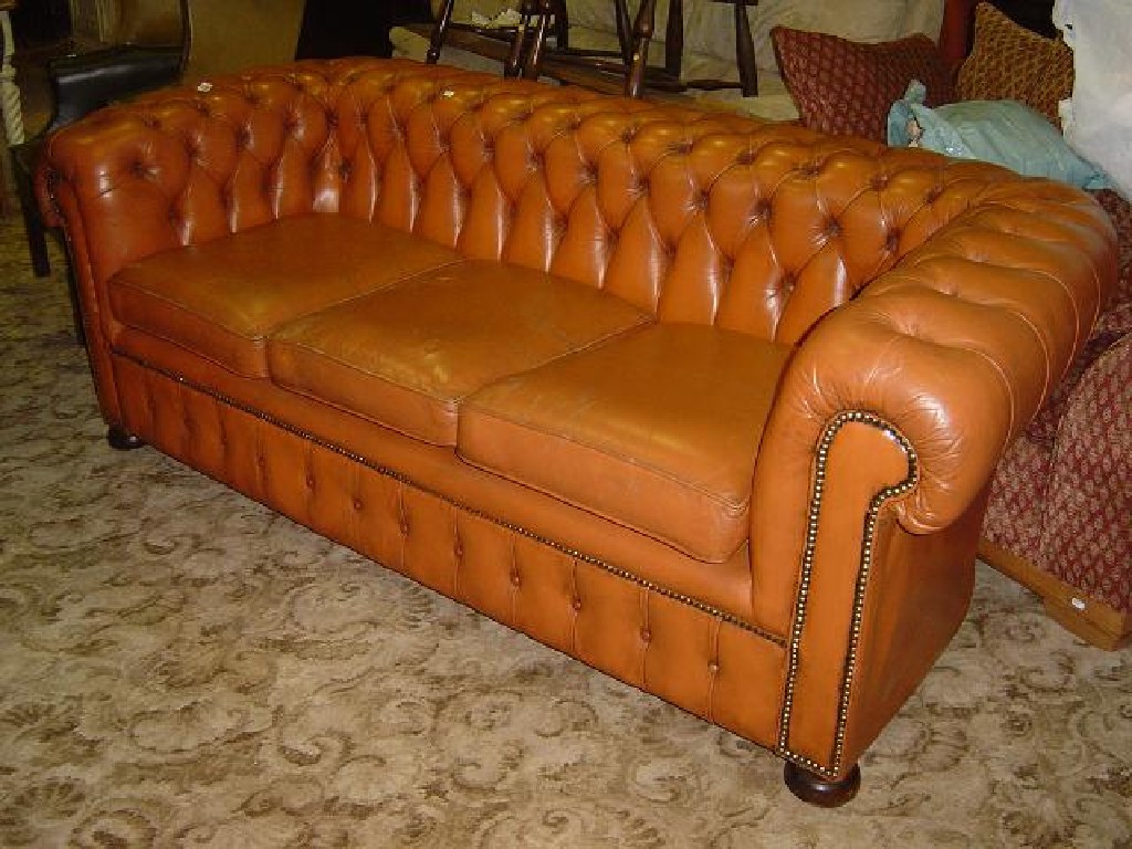 Appraisal: A tan leather three seat Chesterfield sofa with button back