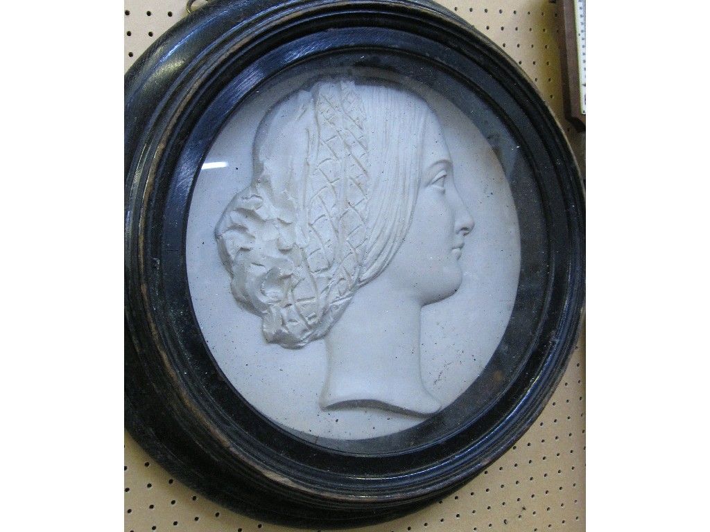 Appraisal: Ebonised circular framed relief plaque of a woman's head