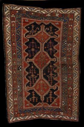 Appraisal: PERSIAN RUG The cobalt field with stepped terracotta octagons joined