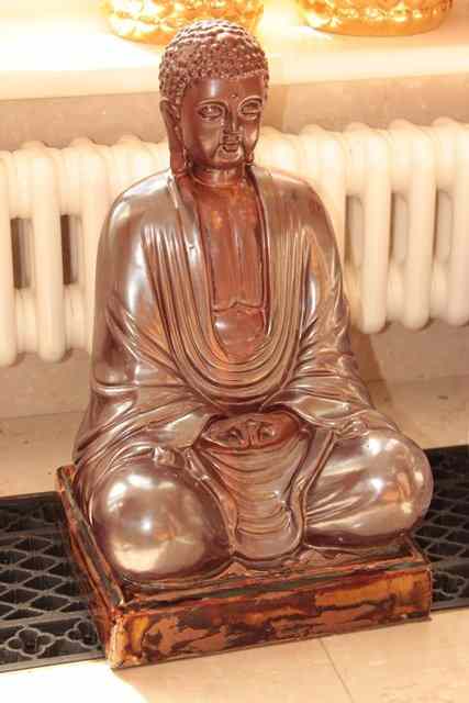 Appraisal: A BROWN GLAZE POTTERY FIGURE of the seated Buddha together