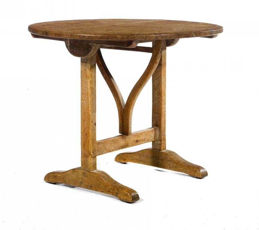 Appraisal: A COTSWOLD SCHOOL OAK FOLDING TABLE the circular top on