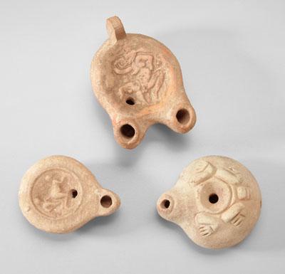 Appraisal: Three ancient terracotta oil lamps two with erotic scenes in