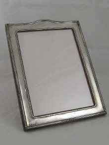 Appraisal: A silver photo frame with cresting rail and oak strut