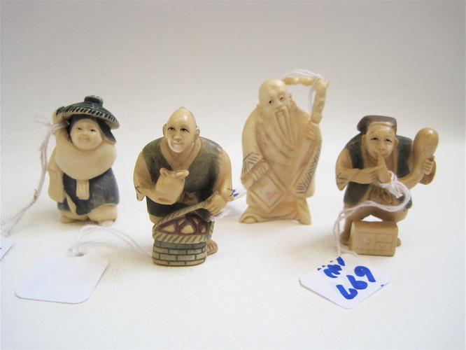 Appraisal: FOUR IVORY CARVED NETSUKE sage standing with staff man blowing