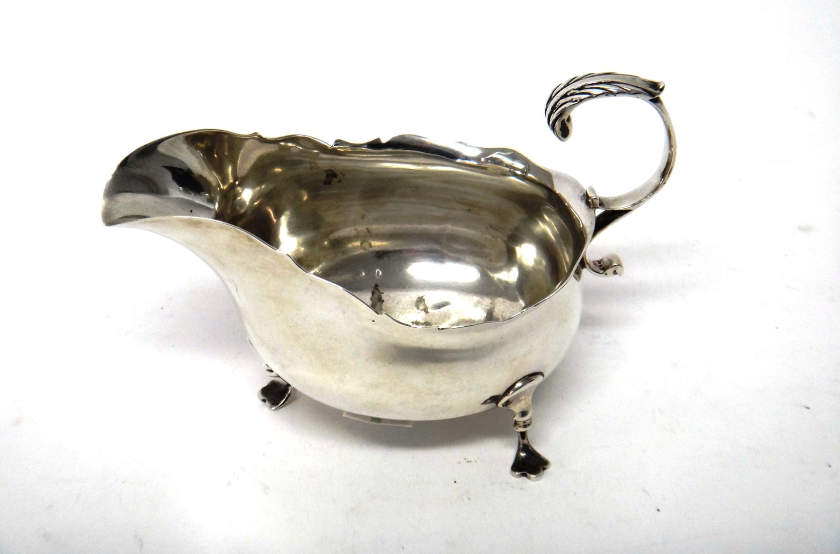 Appraisal: A late Victorian silver sauceboat with a shaped rim scrolling