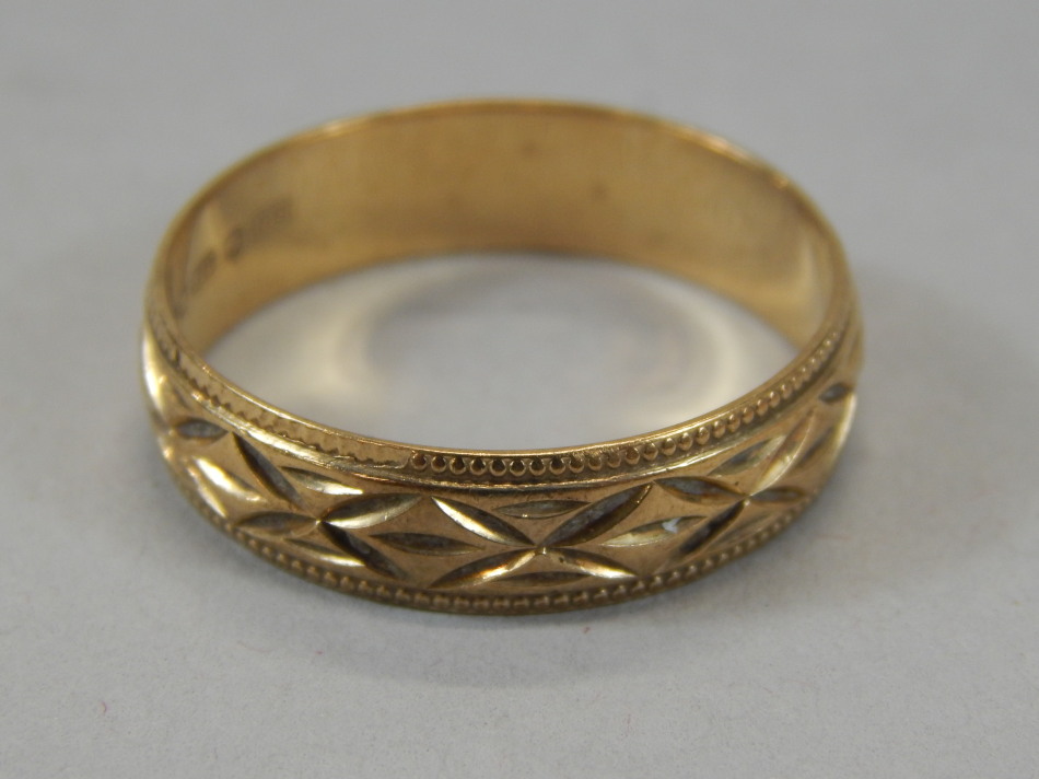 Appraisal: A wedding band of part textured geometric outline yellow metal