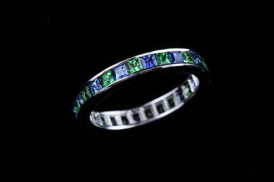 Appraisal: PLATINUM BLUE SAPPHIRE AND TSAVORITE GARNET BAND Channel-set with square-cut