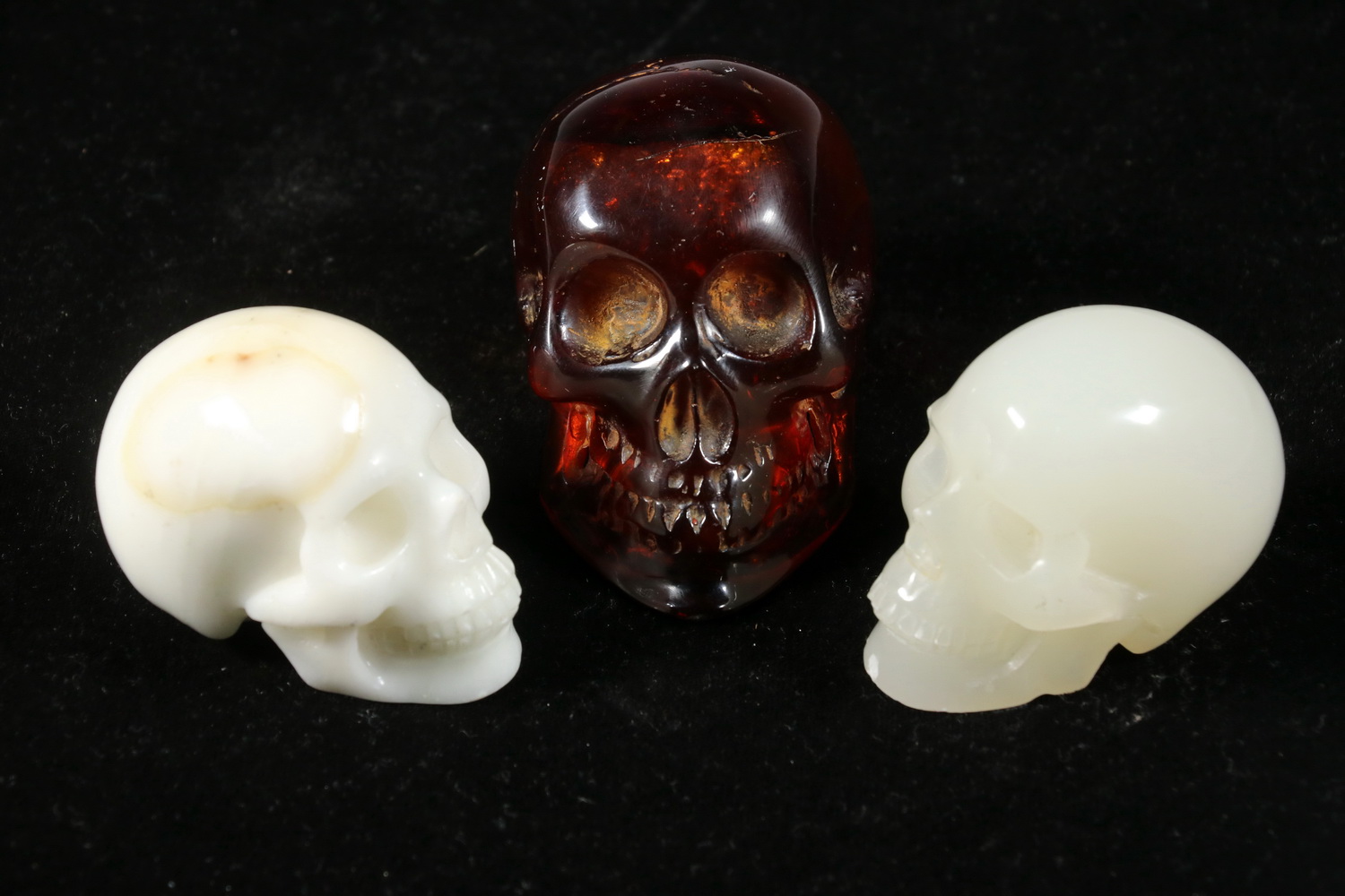 Appraisal: SMALL CARVED CHINESE SKULLS Including Amber with angular jaw tall