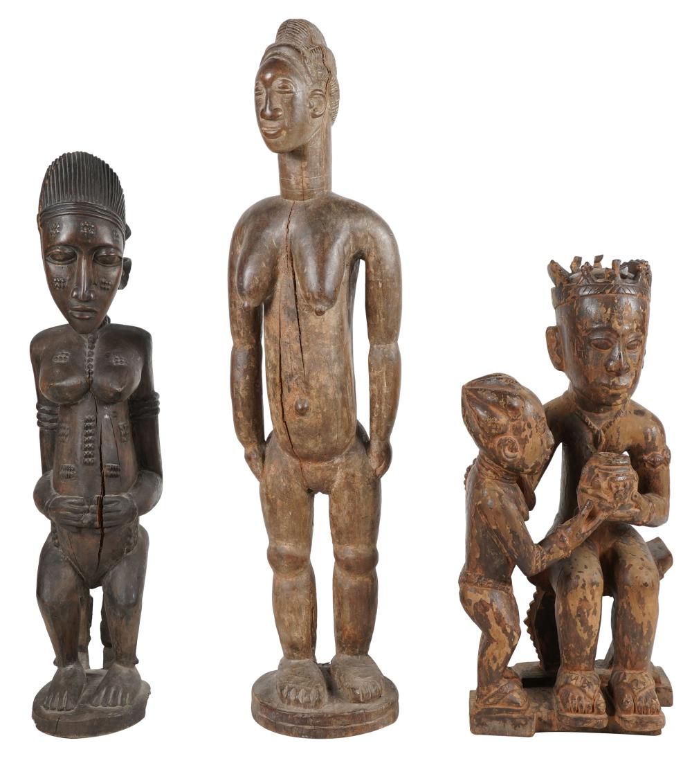 Appraisal: THREE AFRICAN WOOD CARVINGScomprising a seated maternity figure a standing