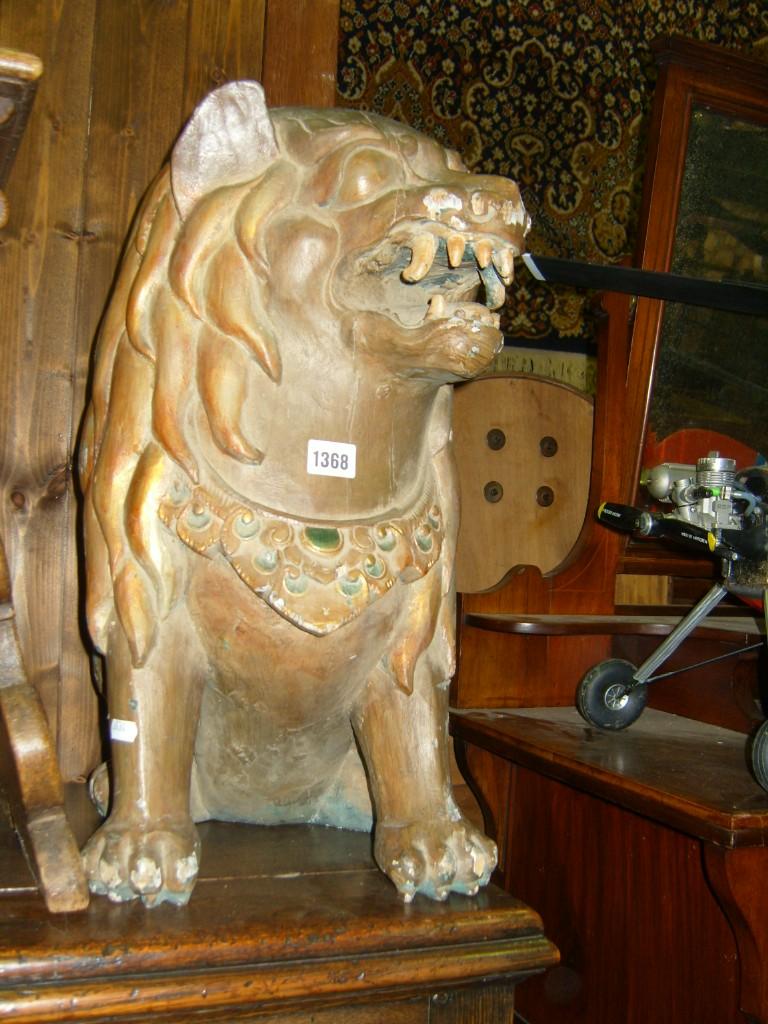 Appraisal: A carved timber figure of a seated mythical lion with