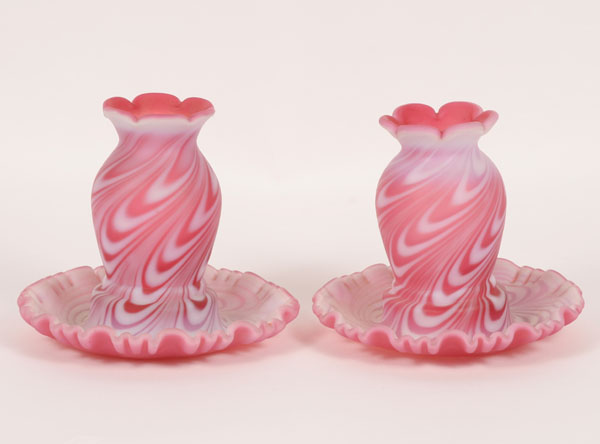 Appraisal: A pair of cranberry glass and opaque swirl candle covers