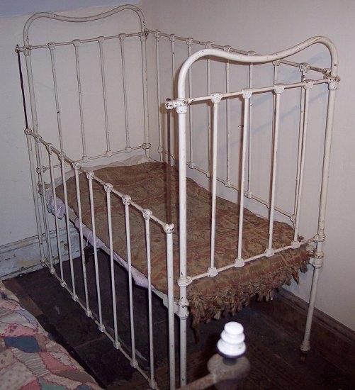 Appraisal: An Edwardian white painted iron framed cot with sliding side