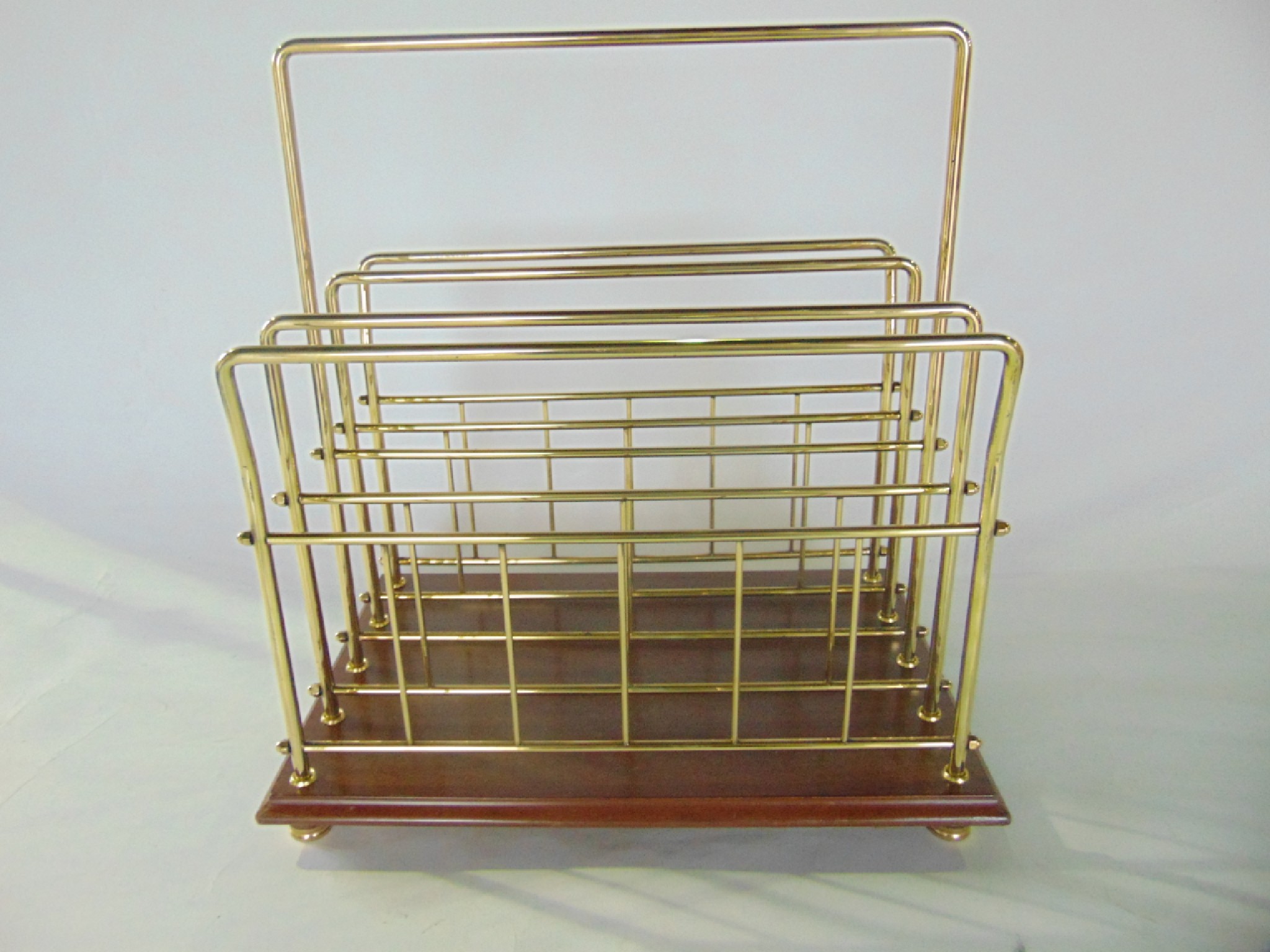 Appraisal: A brass magazine paper rack raised on a polished timber