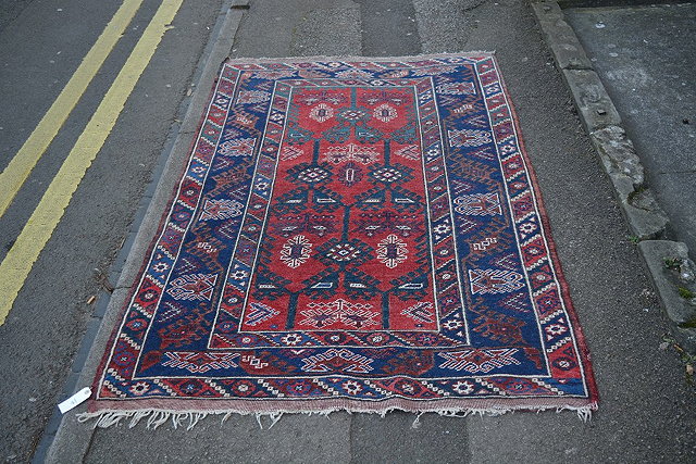 Appraisal: An Afghan red and blue ground rugwith stylised medallions cm