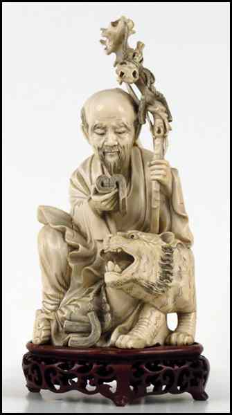 Appraisal: CHINESE CARVED IVORY FIGURE OF A MAN WITH A FOO