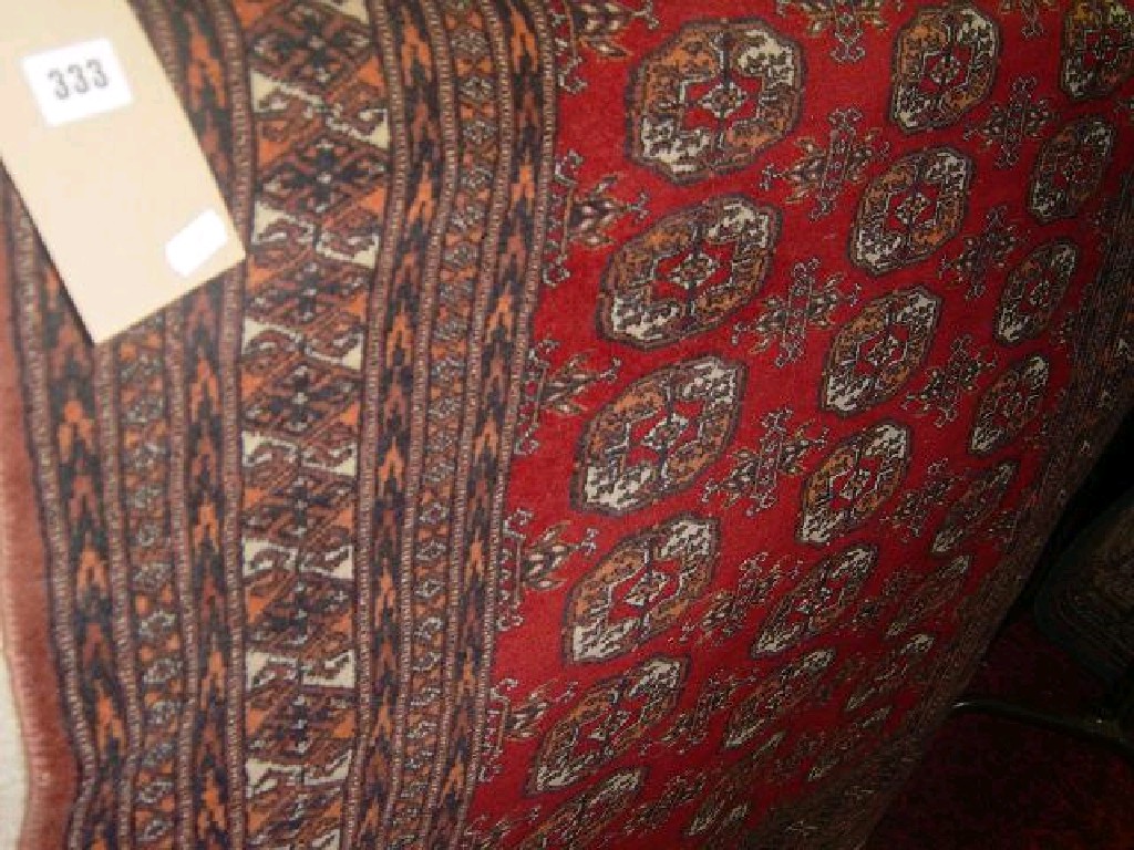 Appraisal: A red ground Eastern wool rug with repeating gul decoration