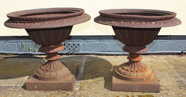 Appraisal: A PAIR OF SHALLOW CAST IRON URNS with turned supports