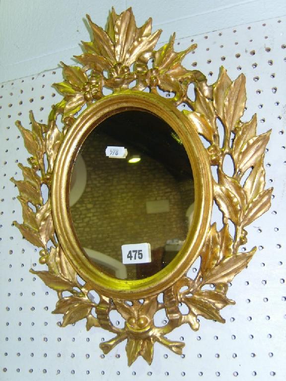 Appraisal: An oval mirror with carved and gilded wooden frame in