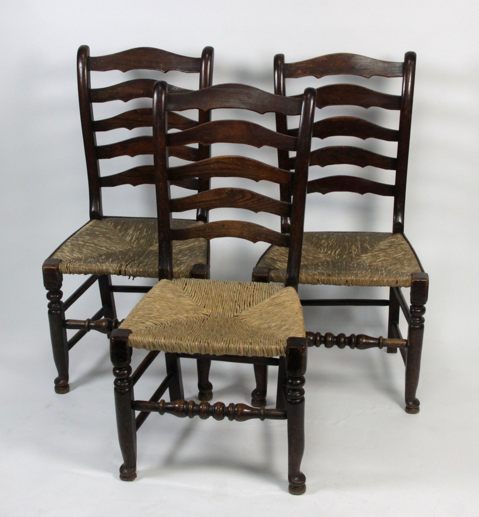 Appraisal: A set of three ladder back chairs with rush seats