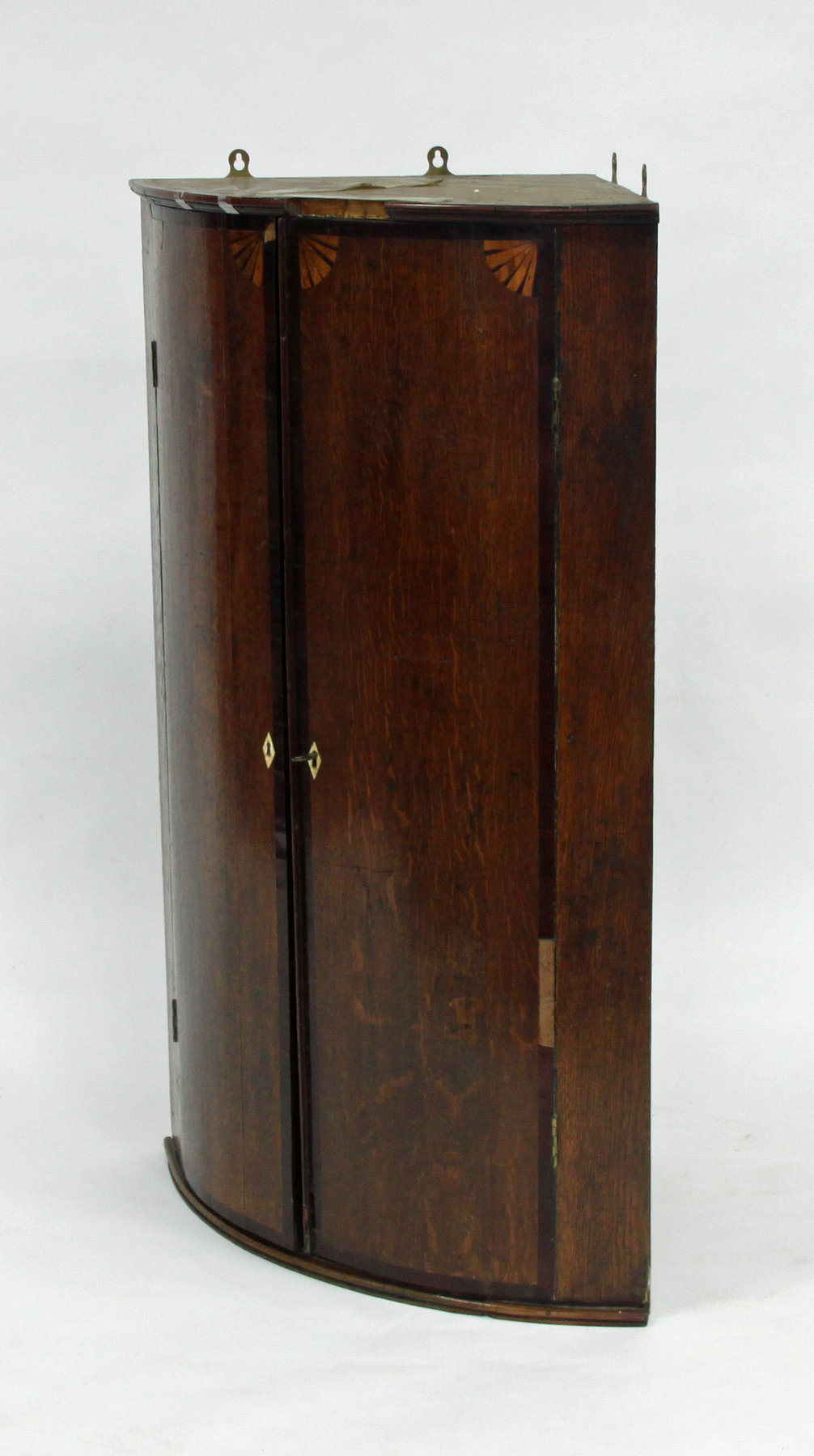 Appraisal: An oak bowfronted corner cupboard circa with fan spandrels