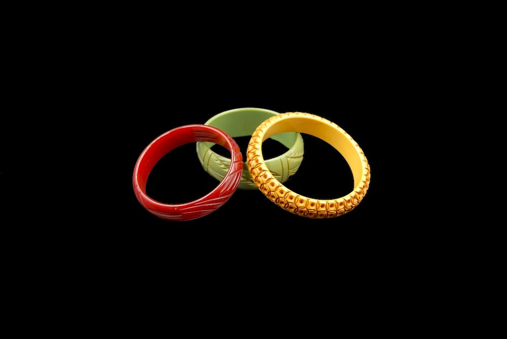 Appraisal: Carved Bangle Bracelets Cherry Red Caramel Green Carved Bangle Bracelets