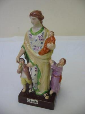 Appraisal: A STAFFORDSHIRE PEARLWARE GROUP Charity modelled as a woman in