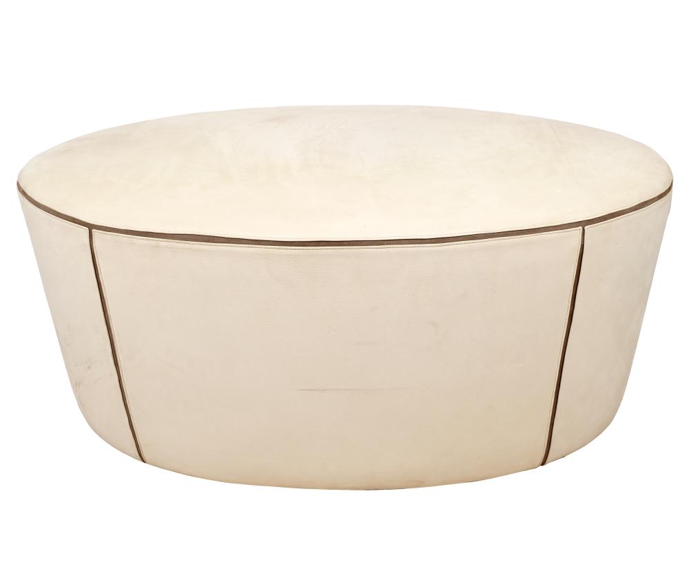 Appraisal: OVAL SUEDE-UPHOLSTERED OTTOMANno label off-white with grey leather trim Condition