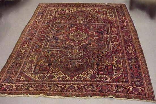 Appraisal: Persian Heriz wool rug soft red background with navy border