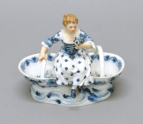 Appraisal: Young girl holding nosegay seated on handled baskets bottom with