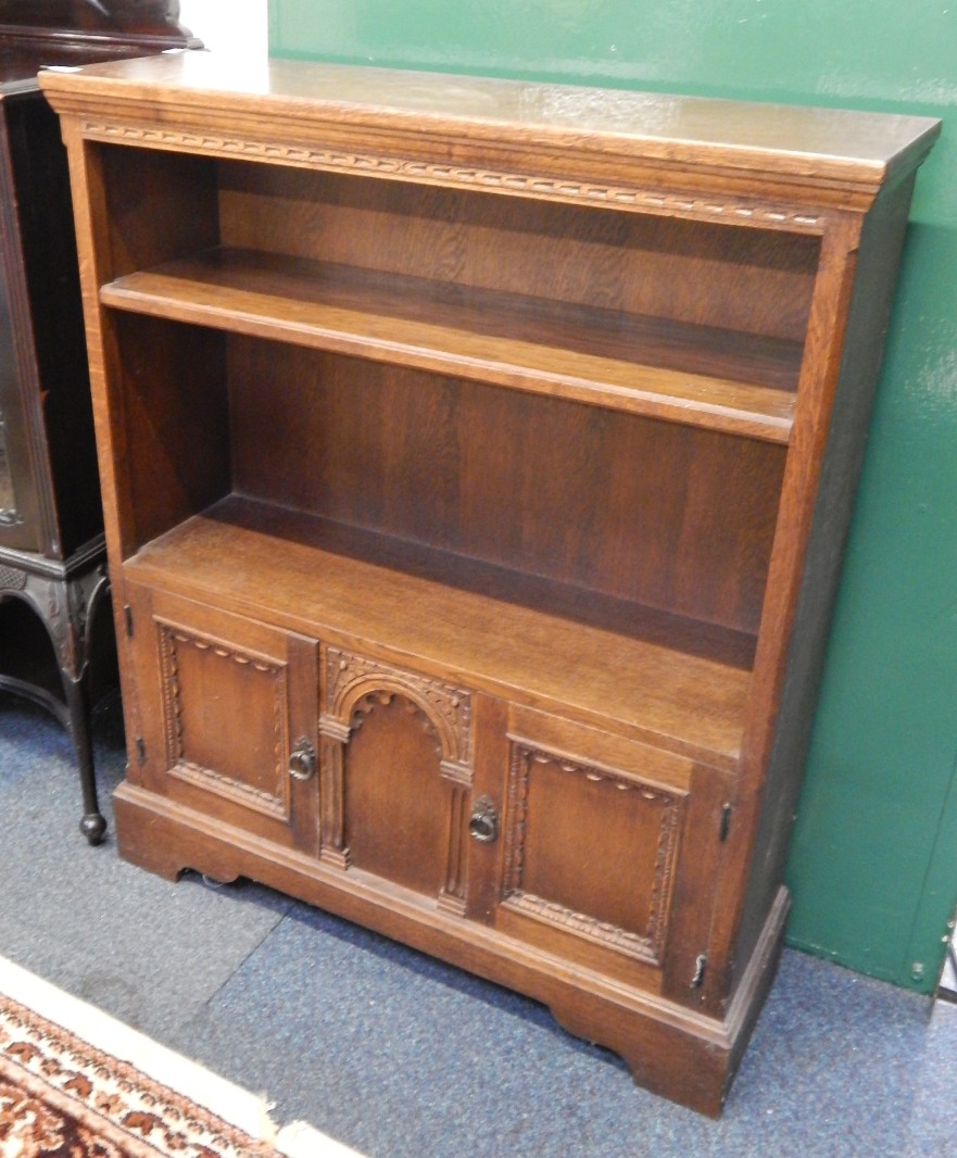 Appraisal: An oak cupboard bookcase with two open shelves over panelled