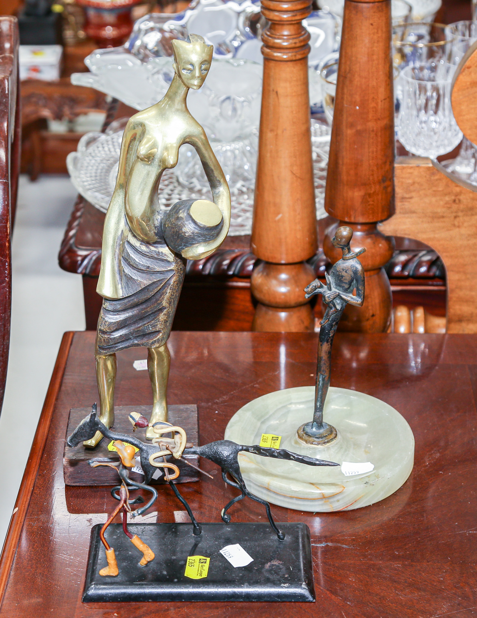 Appraisal: THREE METAL SCULPTURES Including abstract brass figure of a woman