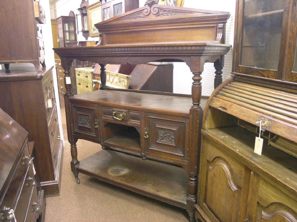 Appraisal: A late Victorian solid oak three tier buffet panelled raised