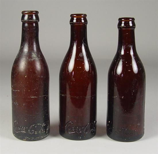 Appraisal: Three Amber Coca-Cola Bottles Circa One approximately high bottle marked