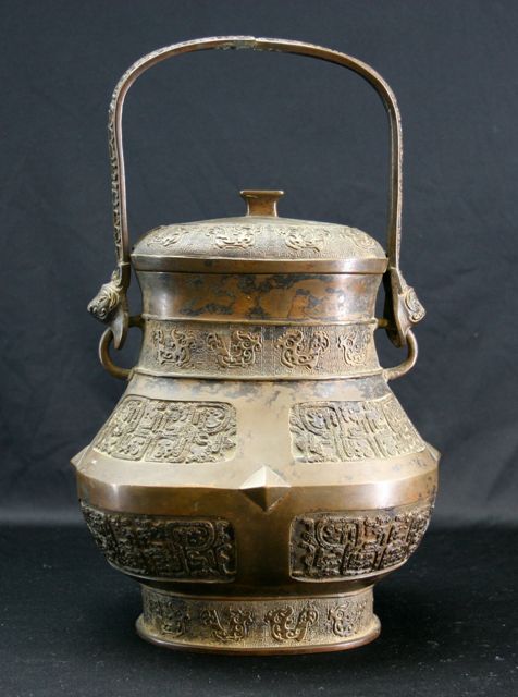 Appraisal: An archaistic bronze wine vessel with swing handle Ming Dynasty