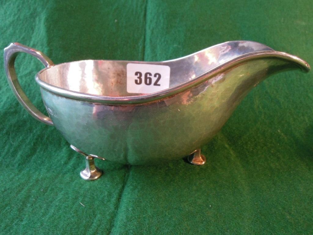 Appraisal: A hammered finished silver gravy boat with loop handle raised