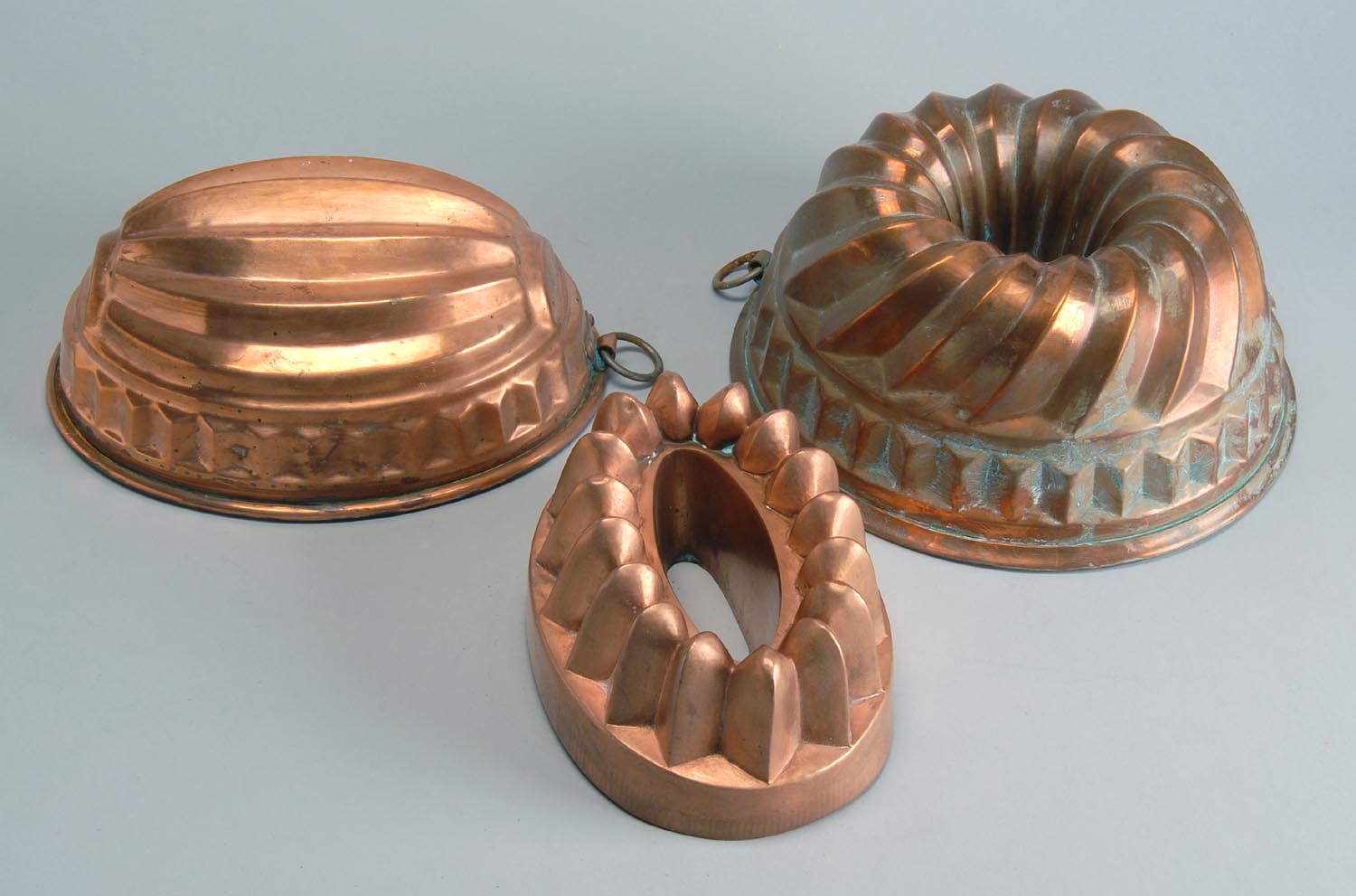 Appraisal: THREE TIN-LINED COPPER PUDDING MOLDS in melon Turk's-head and flower