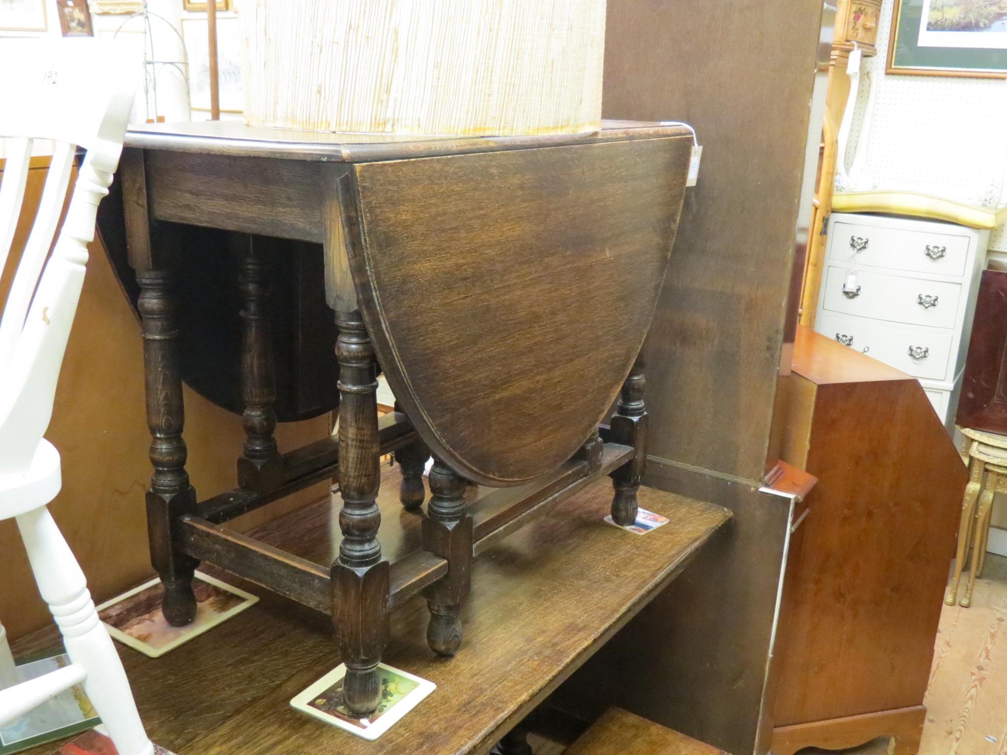 Appraisal: A solid dark oak gateleg dining table on baluster-turned underframe