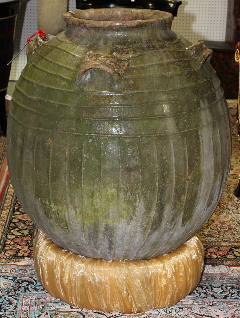 Appraisal: A terracotta oil jar of fluted globular form with green