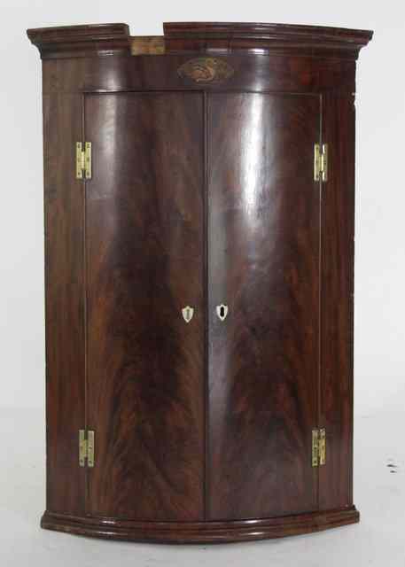 Appraisal: A George III mahogany bowfronted hanging corner cupboard with oval