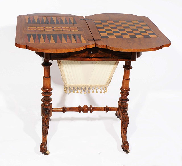 Appraisal: A VICTORIAN WALNUT GAMES AND WORK TABLE the shaped top