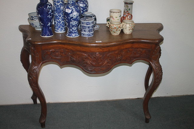 Appraisal: AN INDONESIAN CARVED HARDWOOD SERPENTINE OCCASIONAL TABLE with carved frieze