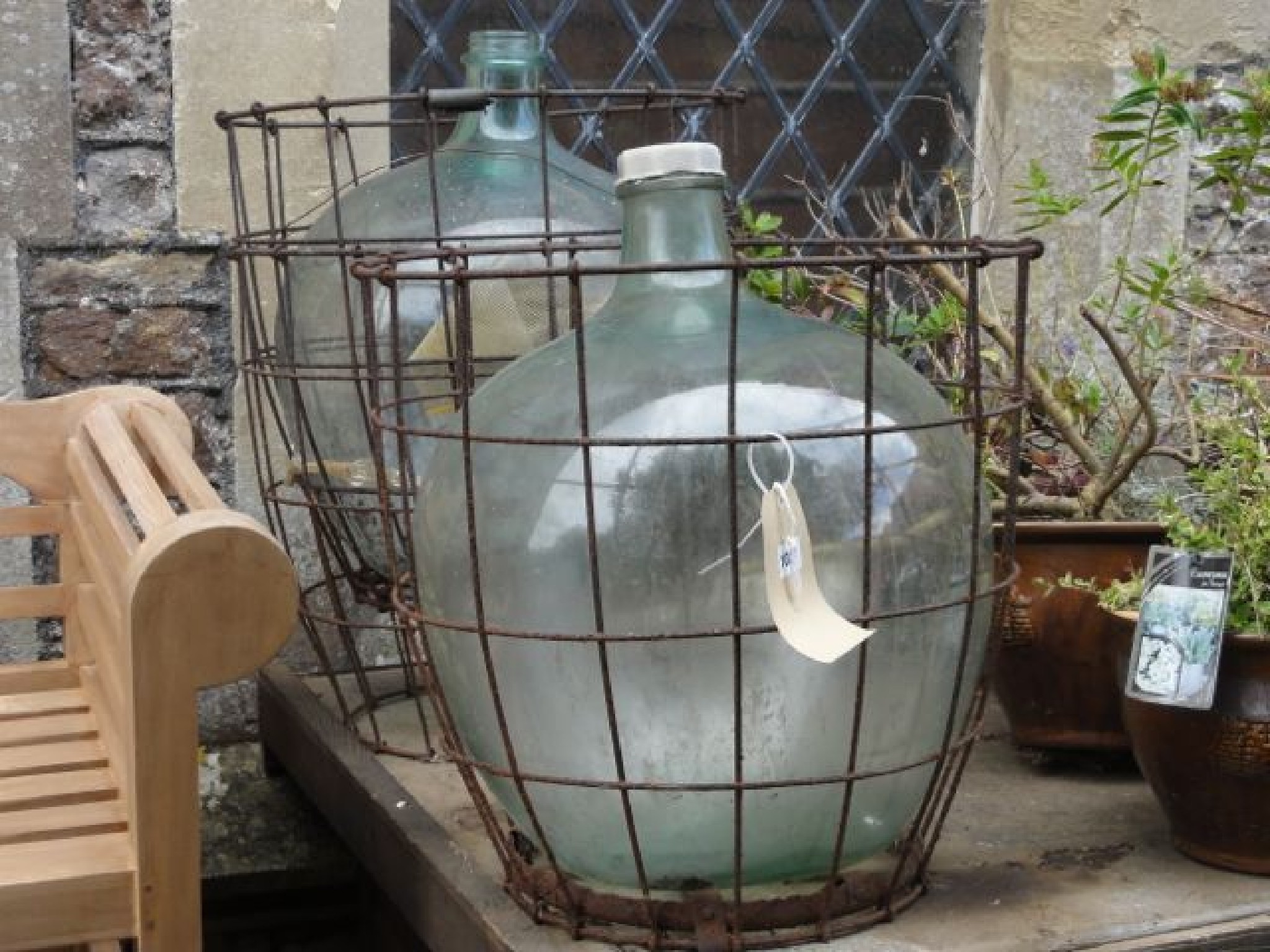 Appraisal: Two green glass carbuoys housed within iron work baskets together