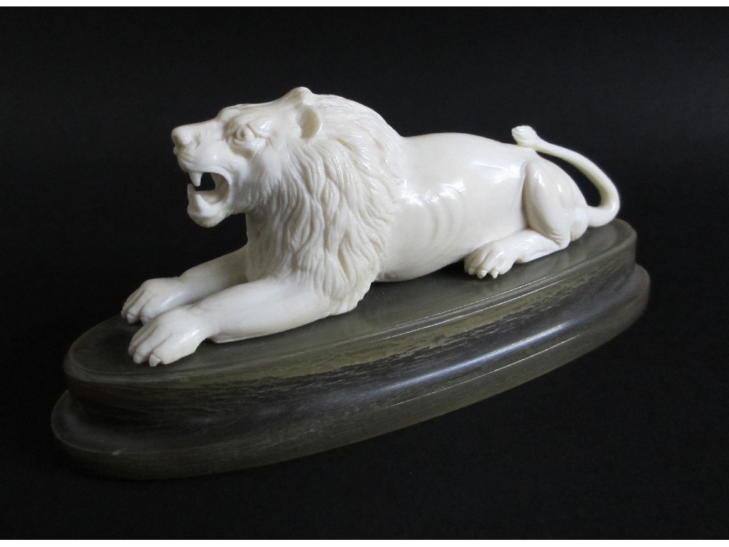 Appraisal: An ivory carving of a lion lying on an oval