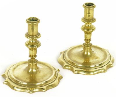 Appraisal: A pair of th century turned brass candlesticks the serpentine