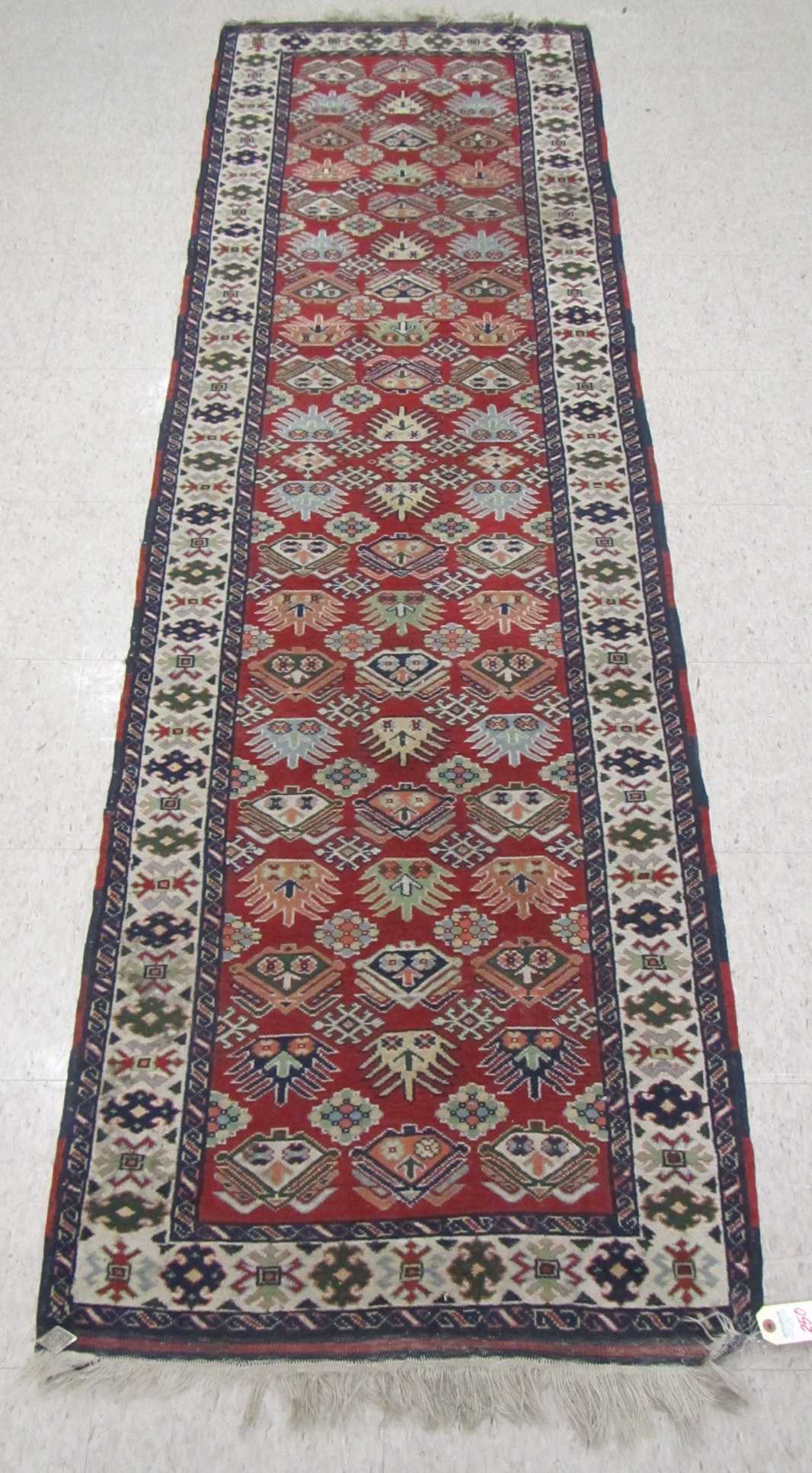 Appraisal: HAND KNOTTED SHIRVAN RUNNER repeating geometric pattern on red ground