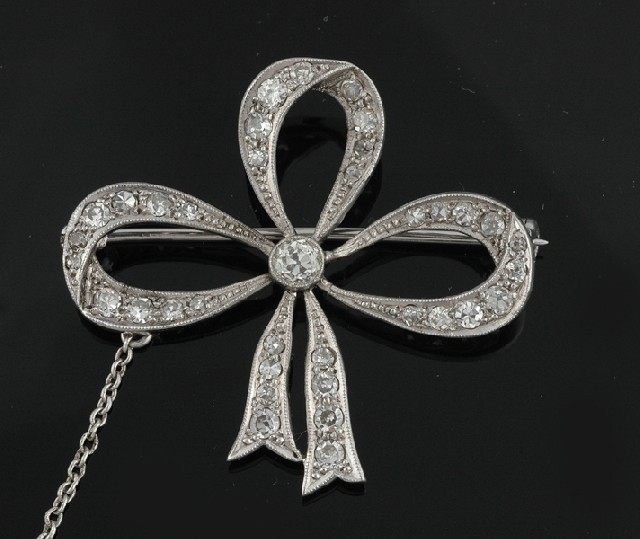 Appraisal: AN EDWARDIAN DIAMOND BROOCH Modelled in platinum as a bow